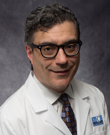 Dmitri samoilov, md smiling in his white coat in front of a backdrop.