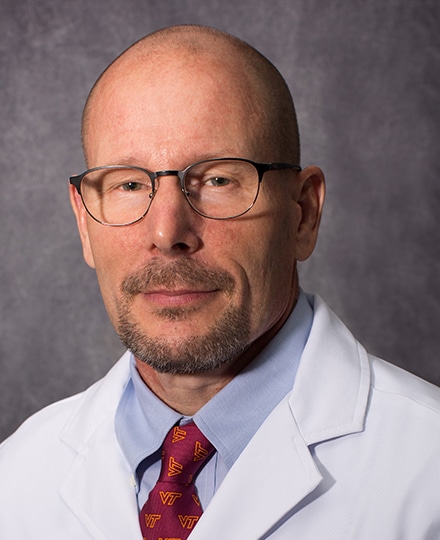 Bennie skinner smiling in his white coat in front of a professional backdrop.