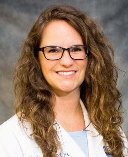 Laura shaw, pa-c. Professional headshot of a medical provider in a white coat and glasses, smiling against a gray background.