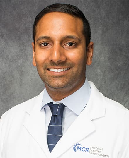 Shashidhara murthy smiling in a white coat against a professional grey backdrop