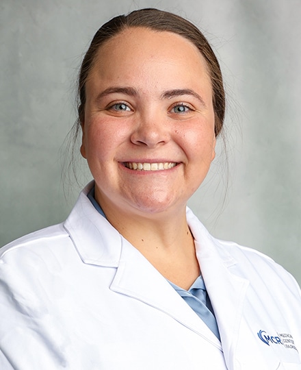Meet rachel abel. Professional headshot of a medical provider wearing a white coat and smiling against a soft gray background.