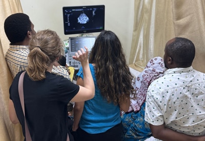 Medical professionals gather around an ultrasound machine while dr. Amy farkas provides hands-on training during a rad-aid global health outreach visit in tanzania.
