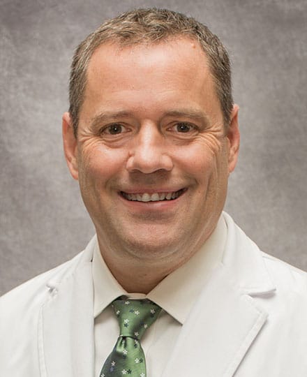 Robert mcclure, md smiling in front of a grey backdrop.