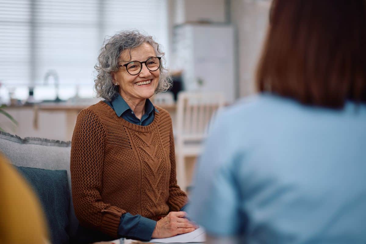 Senior woman smiling while speaking with a medical professional during a radiology care consultation.