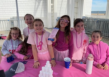 Group of young girls wearing pink at the medical center radiologists booth during a breast cancer awareness walk.