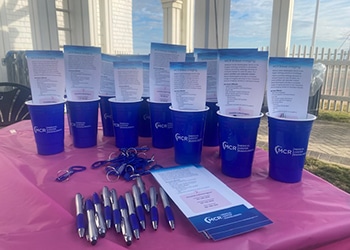 Blue mcr medical center radiologists cups and informational handouts arranged on a pink table at the making strides against breast cancer walk.