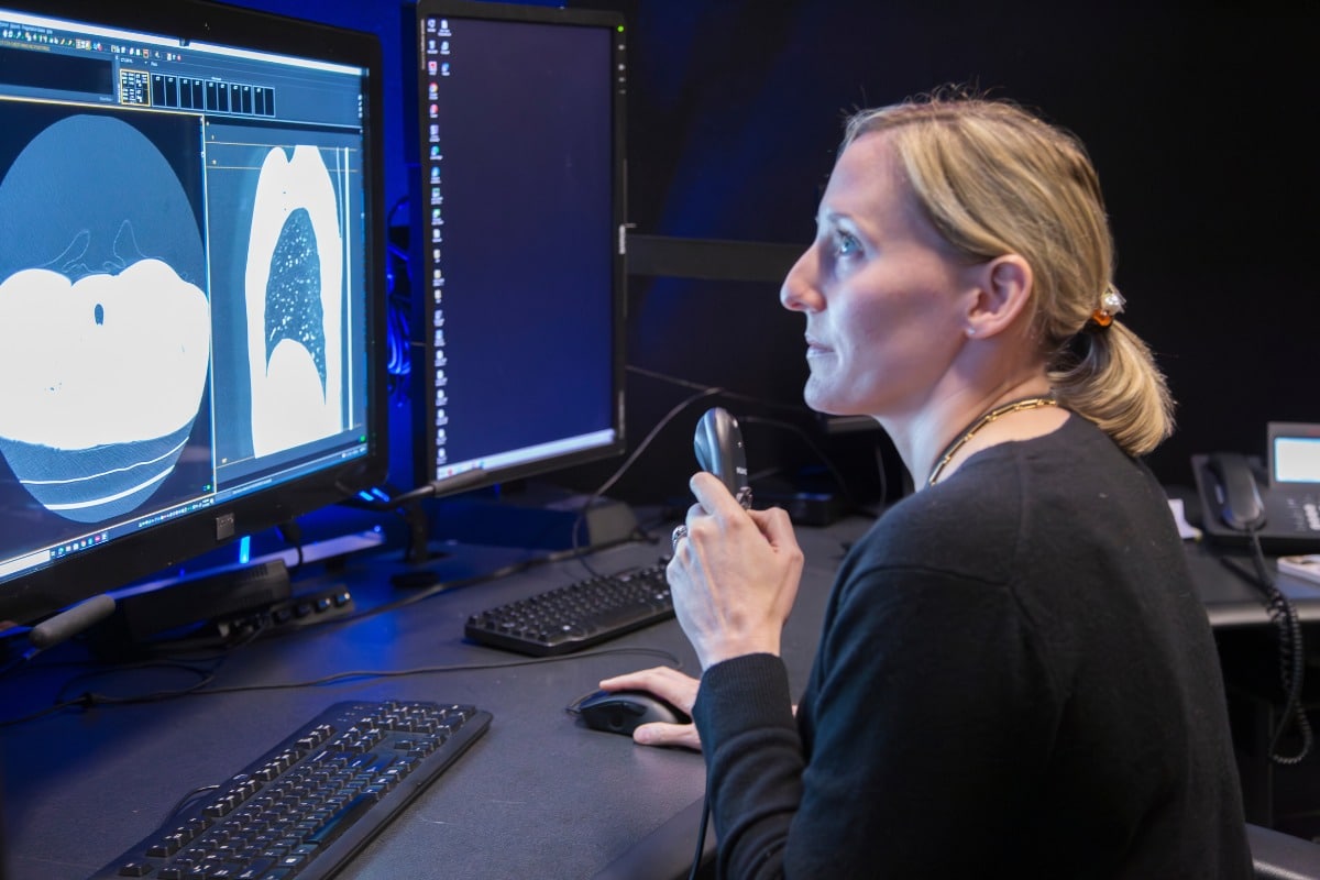 Radiologist reviewing ct scan images on a computer monitor while dictating findings.