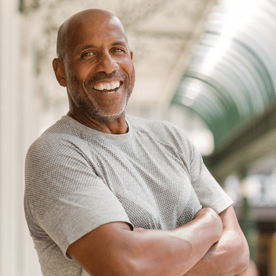 Smiling man in gray shirt, arms crossed, representing vertebral nerve ablation procedure